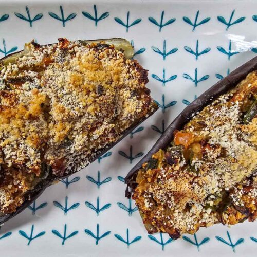 Two stuffed aubergines on a platter with a green pattern.