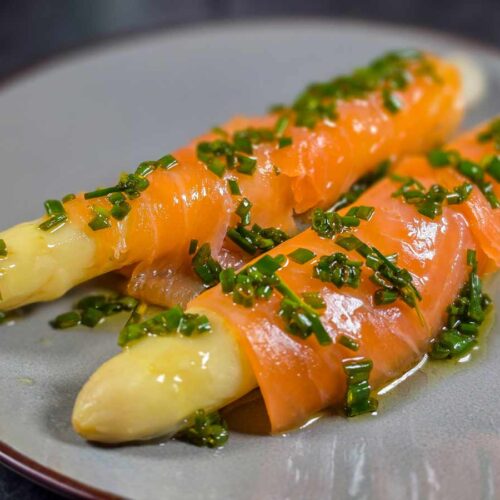 Two spears of white asparagus wrapped with smoked salmon, and dressed with the chives and olive oil dressing